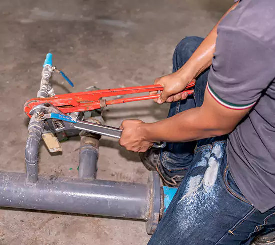 Licensed plumber repairing a copper pipe leak in a Massachusetts basement